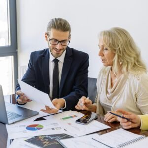 Two business professionals reviewing financial documents and graphs during a meeting.