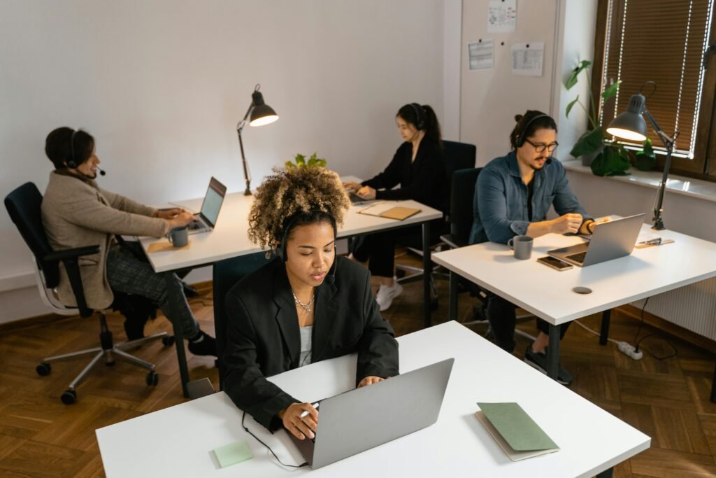 Diverse team of call center agents working at computers in an office setting, focused on tasks.